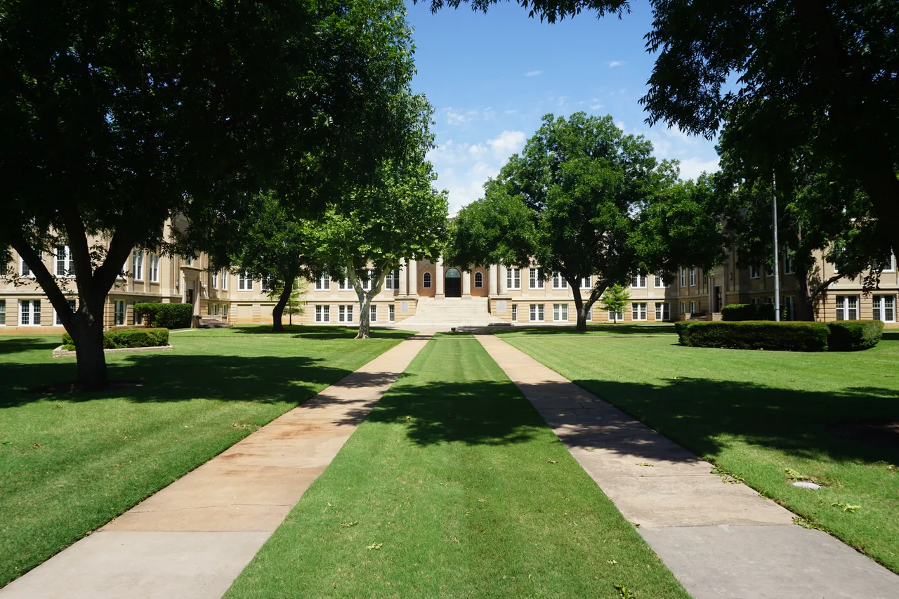 Tree-lined walkways lead across a lawn to the Hardin Administration Building at Abilene Christian University.