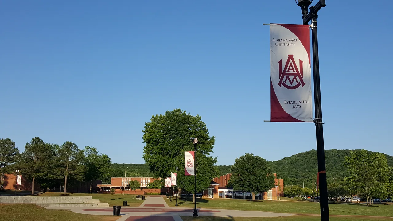 Alabama A&M banners line the Quad walkway beside lawns and campus buildings.