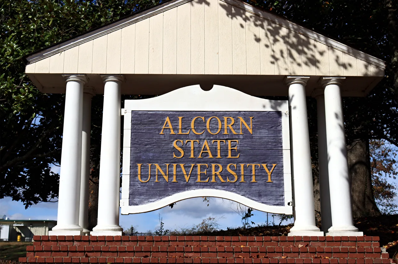 Alcorn State University’s purple and gold entrance sign stands between white columns on a brick base.