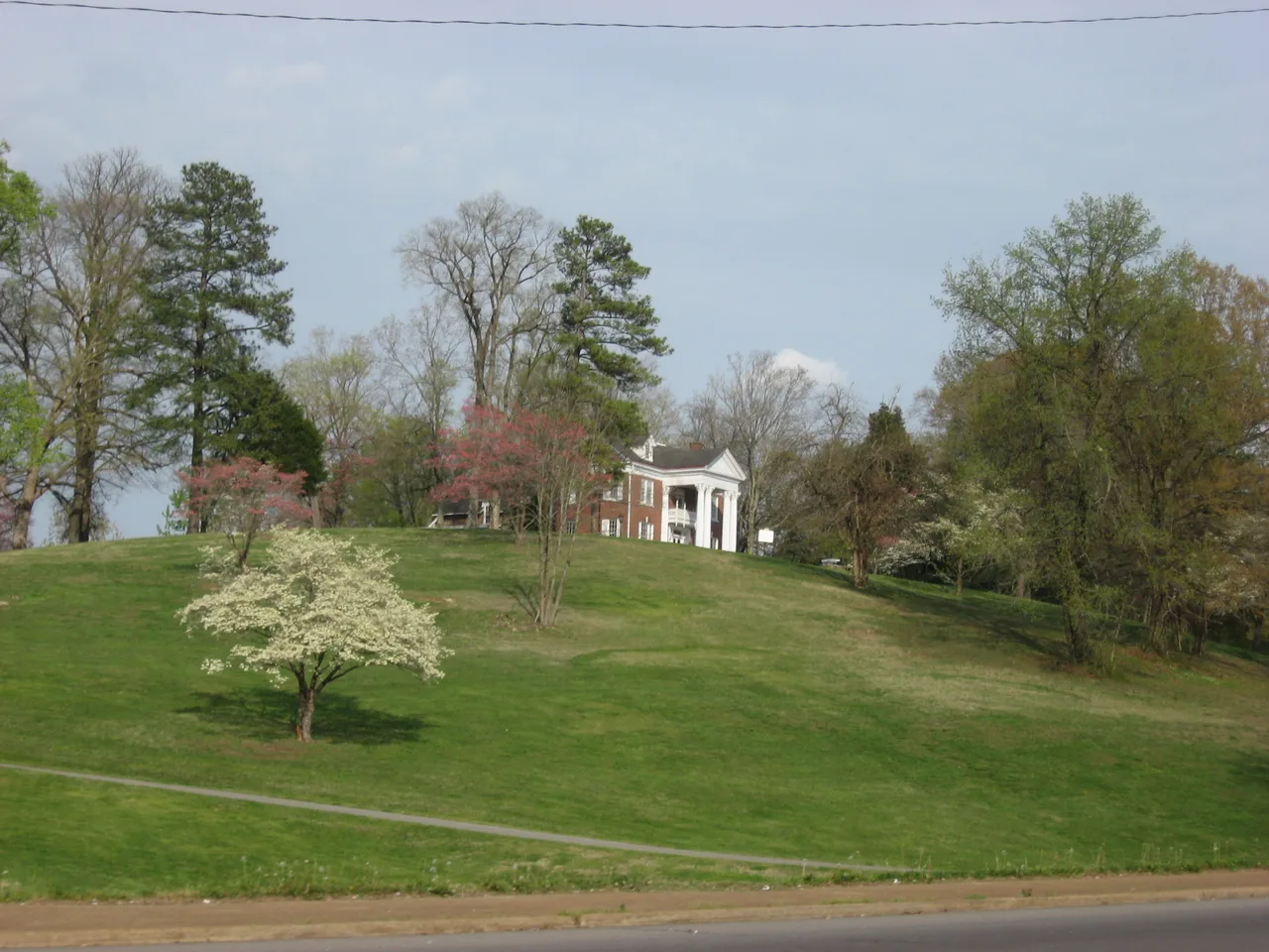 A red-brick mansion with a white portico sits above a tree-lined lawn at Emerald Hill in Clarksville.