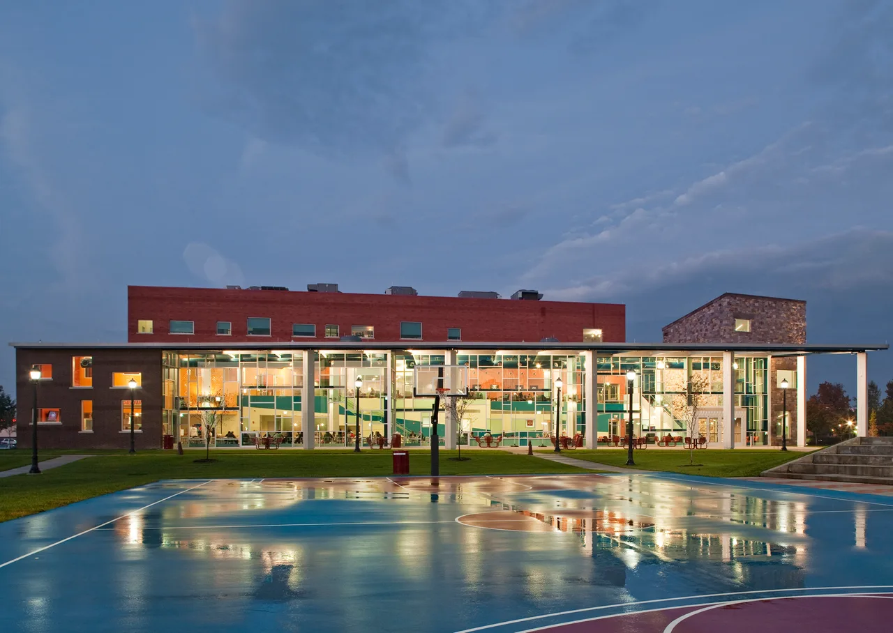 Glass-front Student Center and an outdoor basketball court at Delaware State University at dusk.