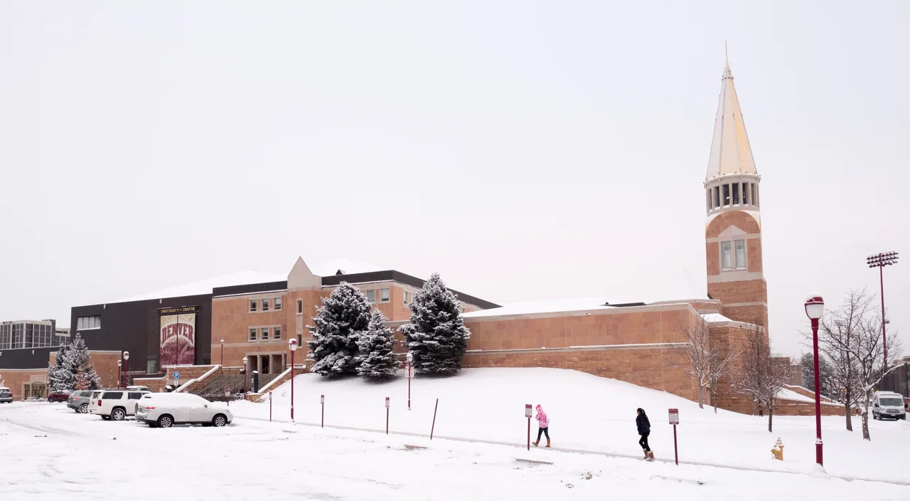 Snow-covered Magness Arena complex and tower at the University of Denver.