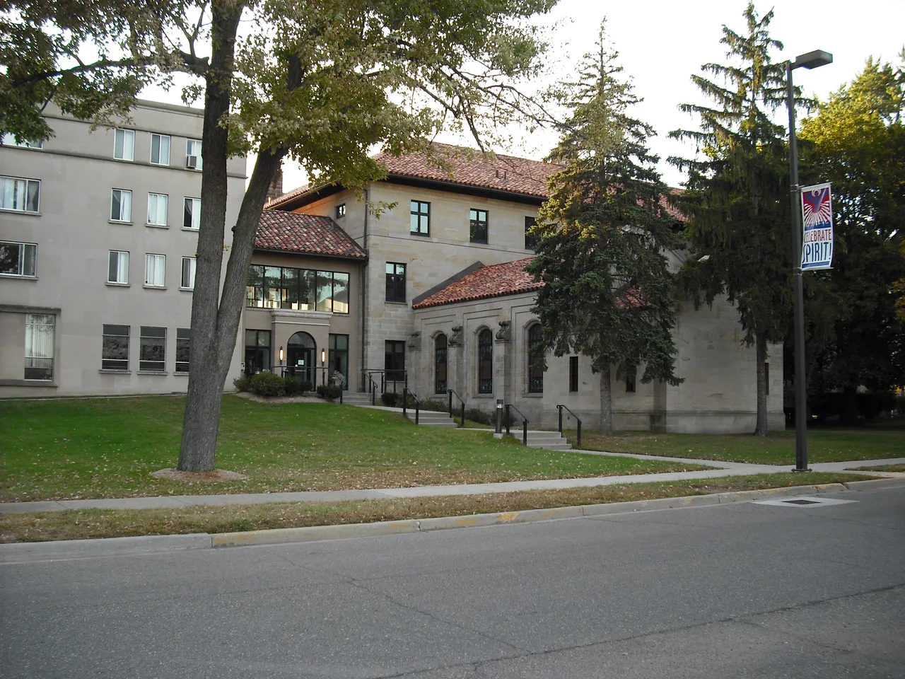 Stone exterior and tiled roofs of Lansing Reilly Hall with lawn and mature trees at the University of Detroit Mercy.