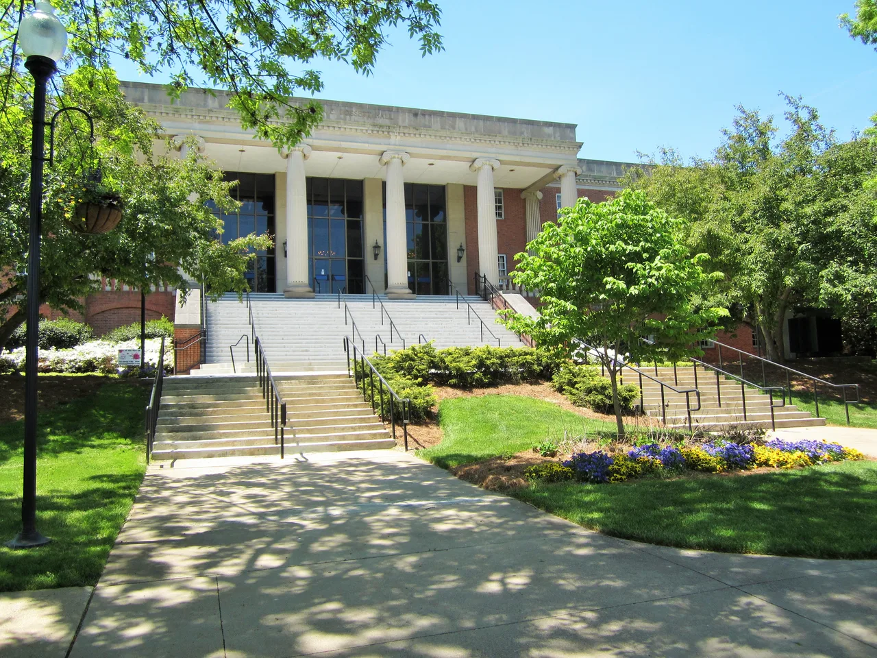 Columned entrance and steps of Dossett Hall among lawn, trees and flower beds at East Tennessee State University.