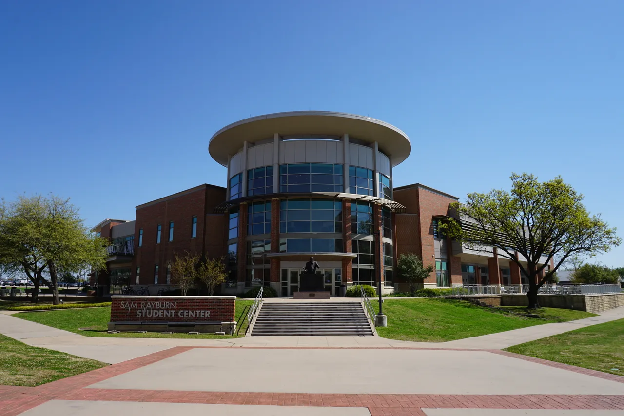 Round glazed entrance, broad steps and lawn at the Rayburn Student Center on the Commerce campus of East Texas A&M University.