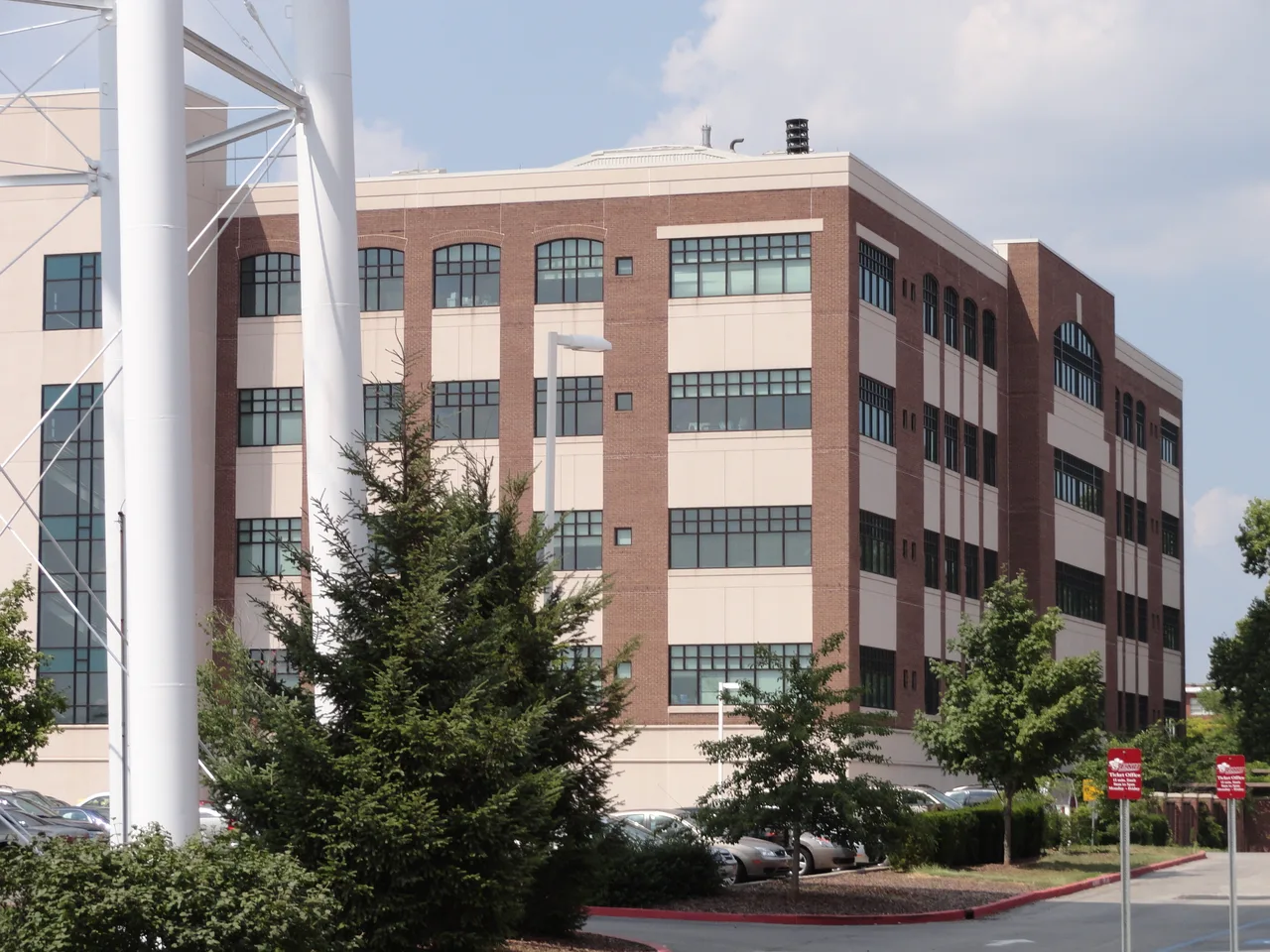 Brick and light-panel campus building at Eastern Kentucky University, with trees and flag supports in the foreground