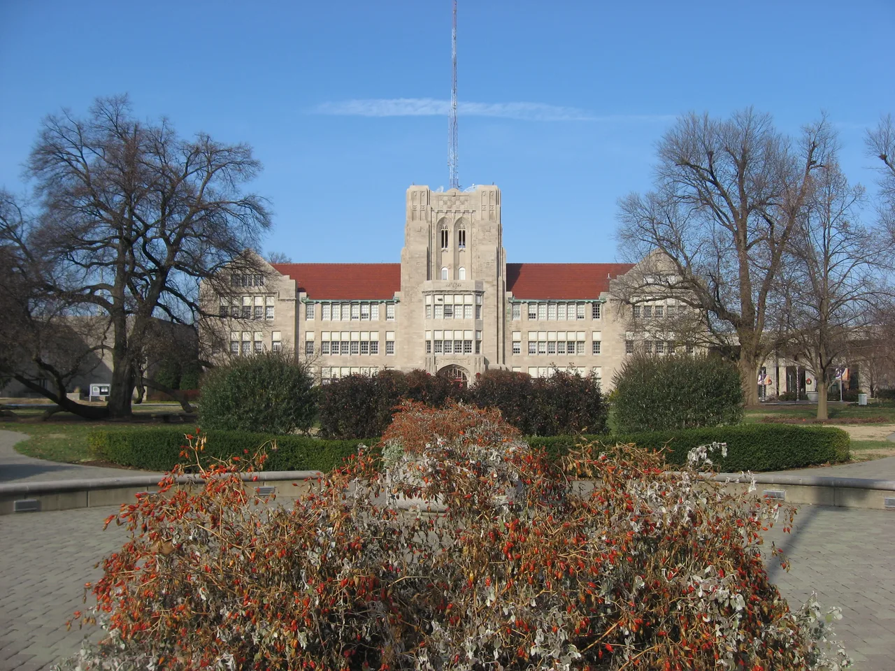 Stone administration building and central tower at the University of Evansville, framed by campus lawns, shrubs and trees
