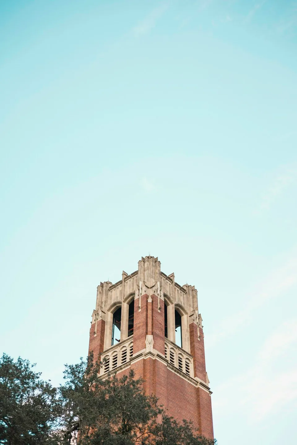 The brick and stone top of Century Tower at the University of Florida beneath a blue sky