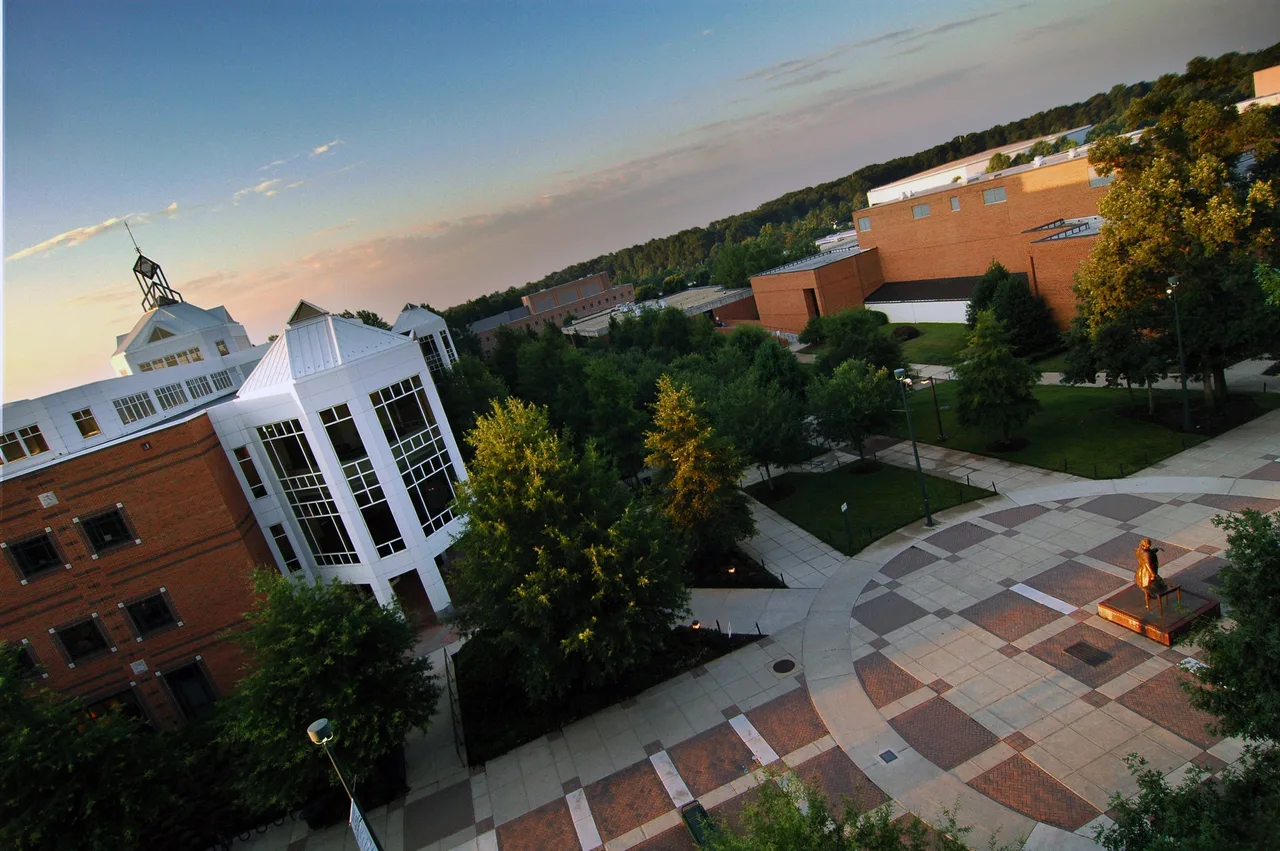 An elevated dawn view of the Johnson Center and adjacent buildings around a courtyard on George Mason University’s Fairfax campus, photographed with a diagonal horizon.