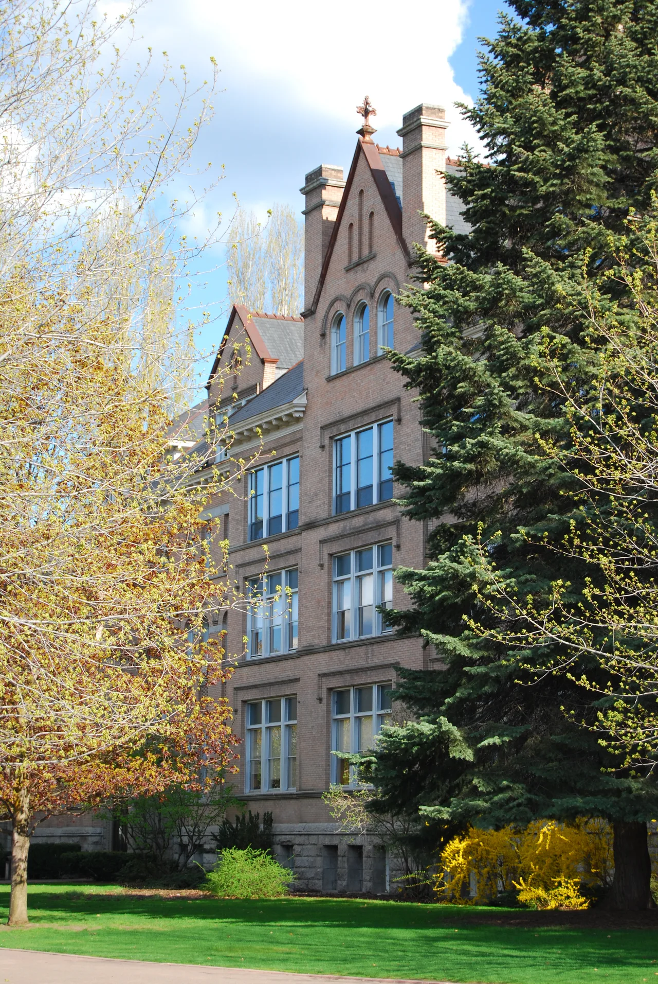 Brick academic building at Gonzaga University framed by spring trees and a green lawn