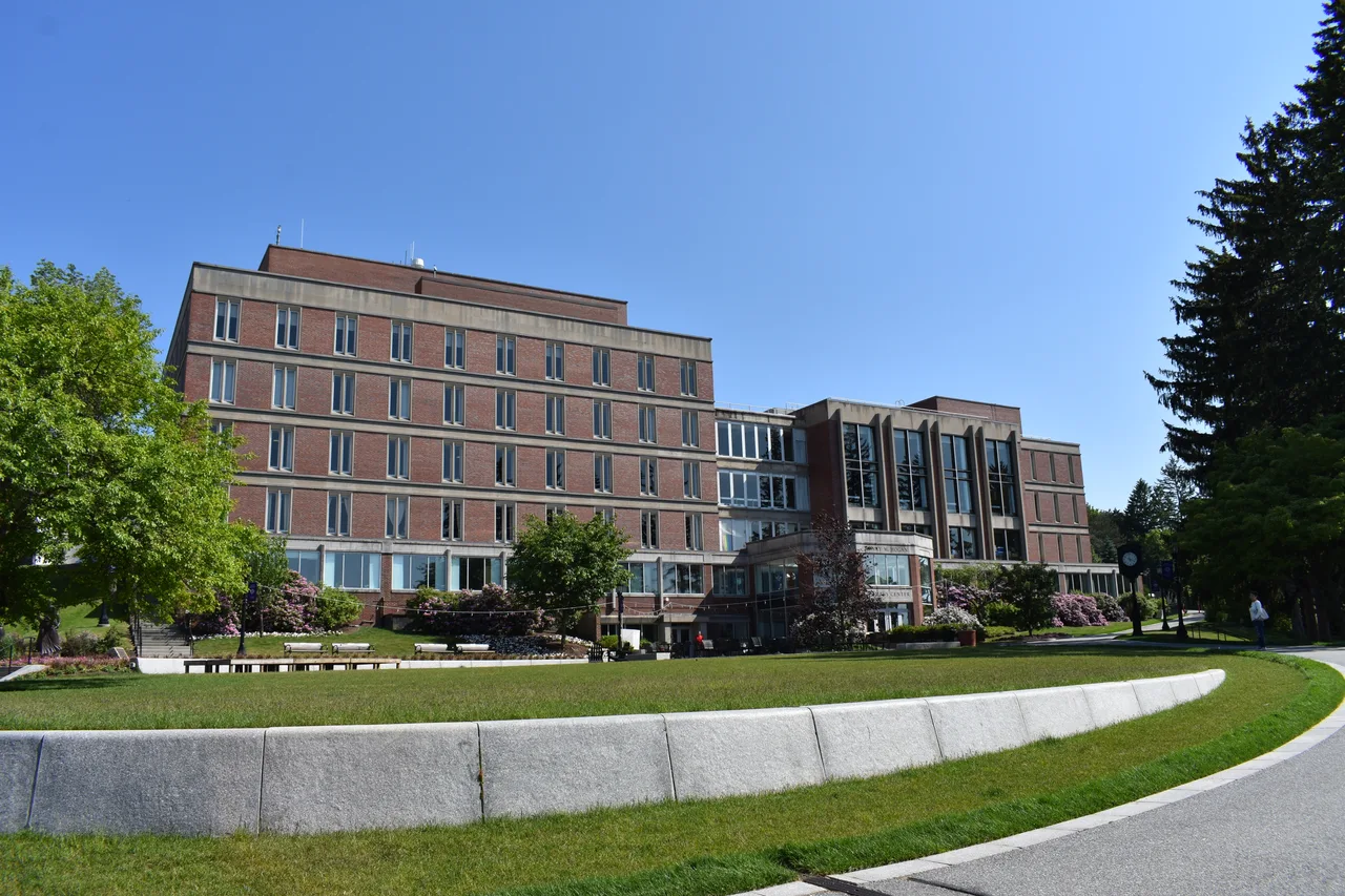 The brick-and-concrete Hogan Campus Center beyond a landscaped lawn and curved low wall at the College of the Holy Cross.