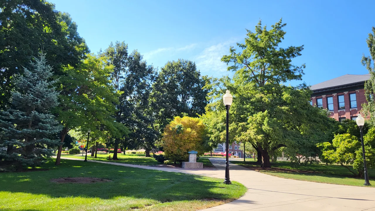 Sunlit paths and lawns among mature trees on Illinois State University’s main quad, with part of Moulton Hall at the right.