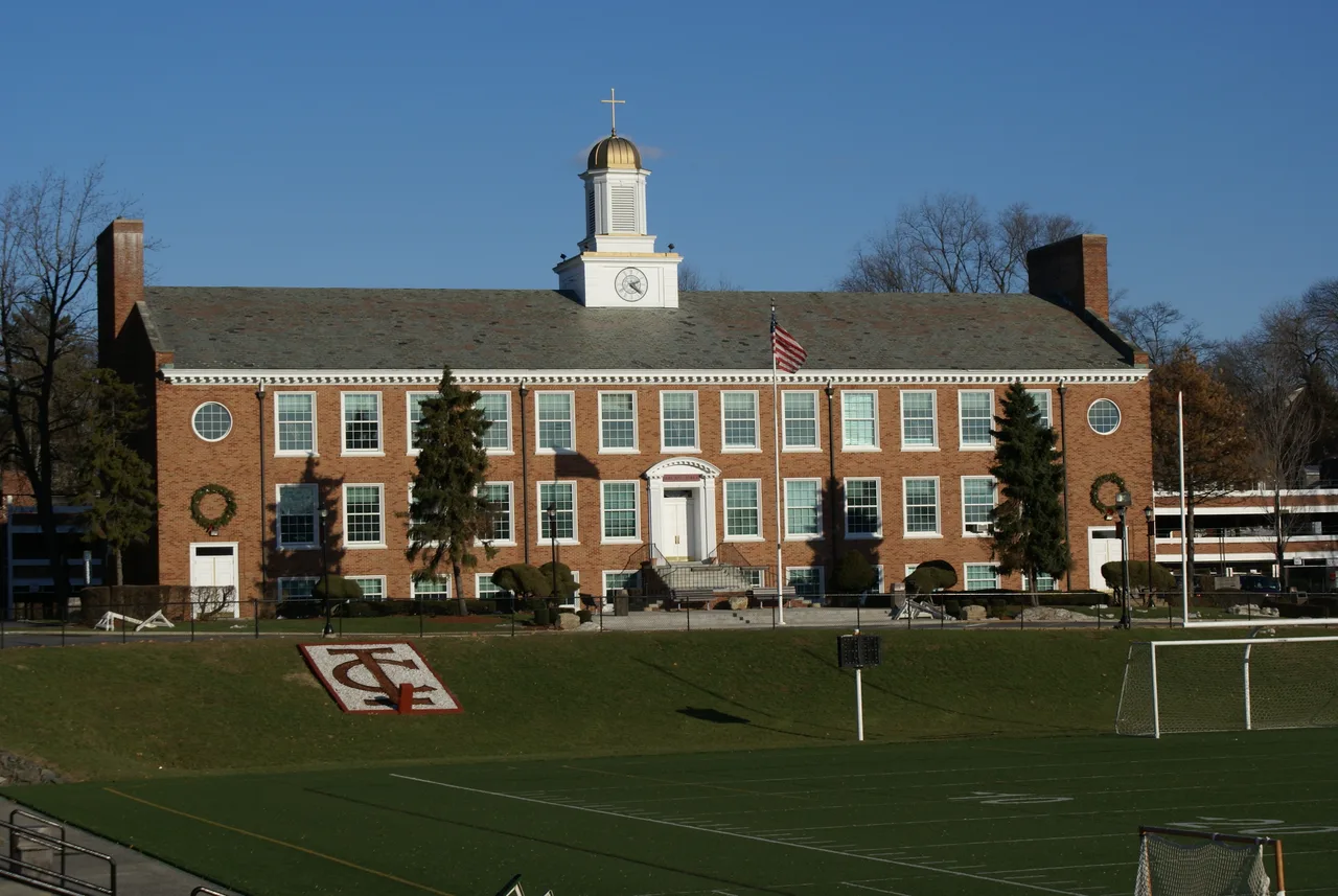 The brick facade and white clock cupola of Hagan Hall, facing a campus playing field at the New Rochelle institution now named Iona University.