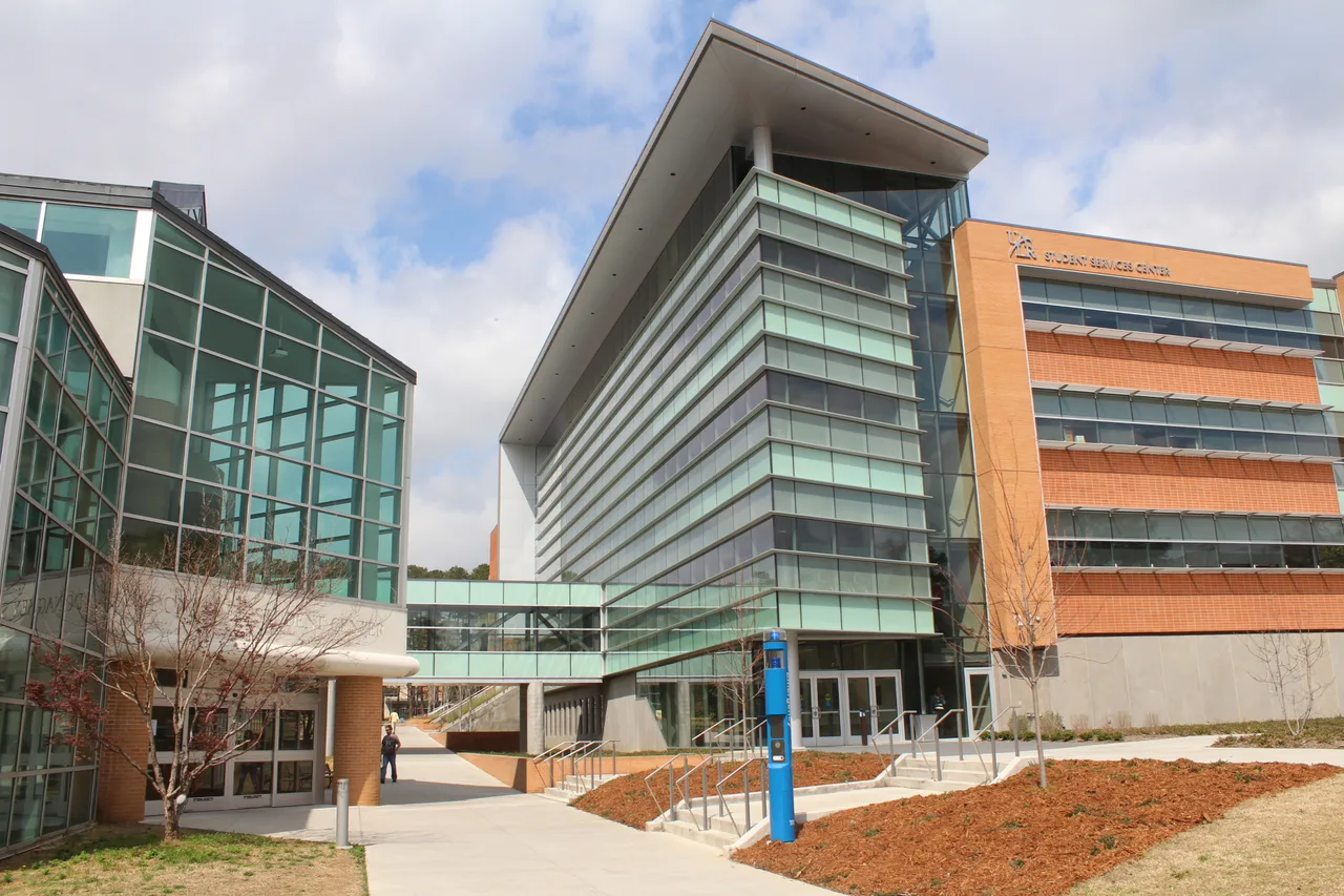 Glass-and-brick Student Services Center with entrance steps and a skywalk at UA Little Rock.