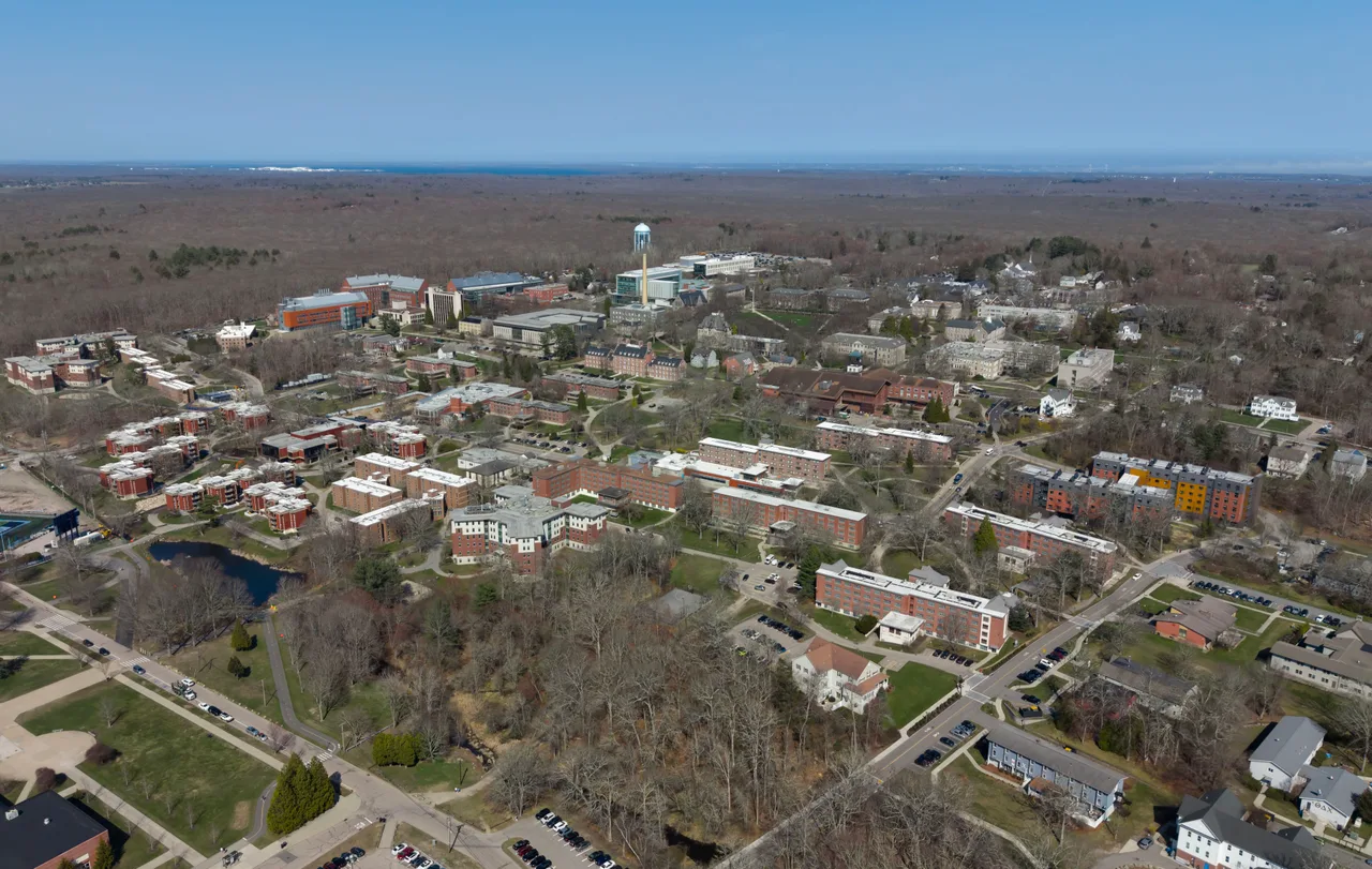 Aerial view of academic and residential buildings, grounds and a pond at the University of Rhode Island’s Kingston campus.