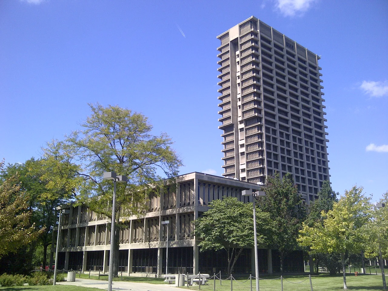 A concrete campus tower and adjoining low building behind lawns, trees and paths at the University of Illinois Chicago.